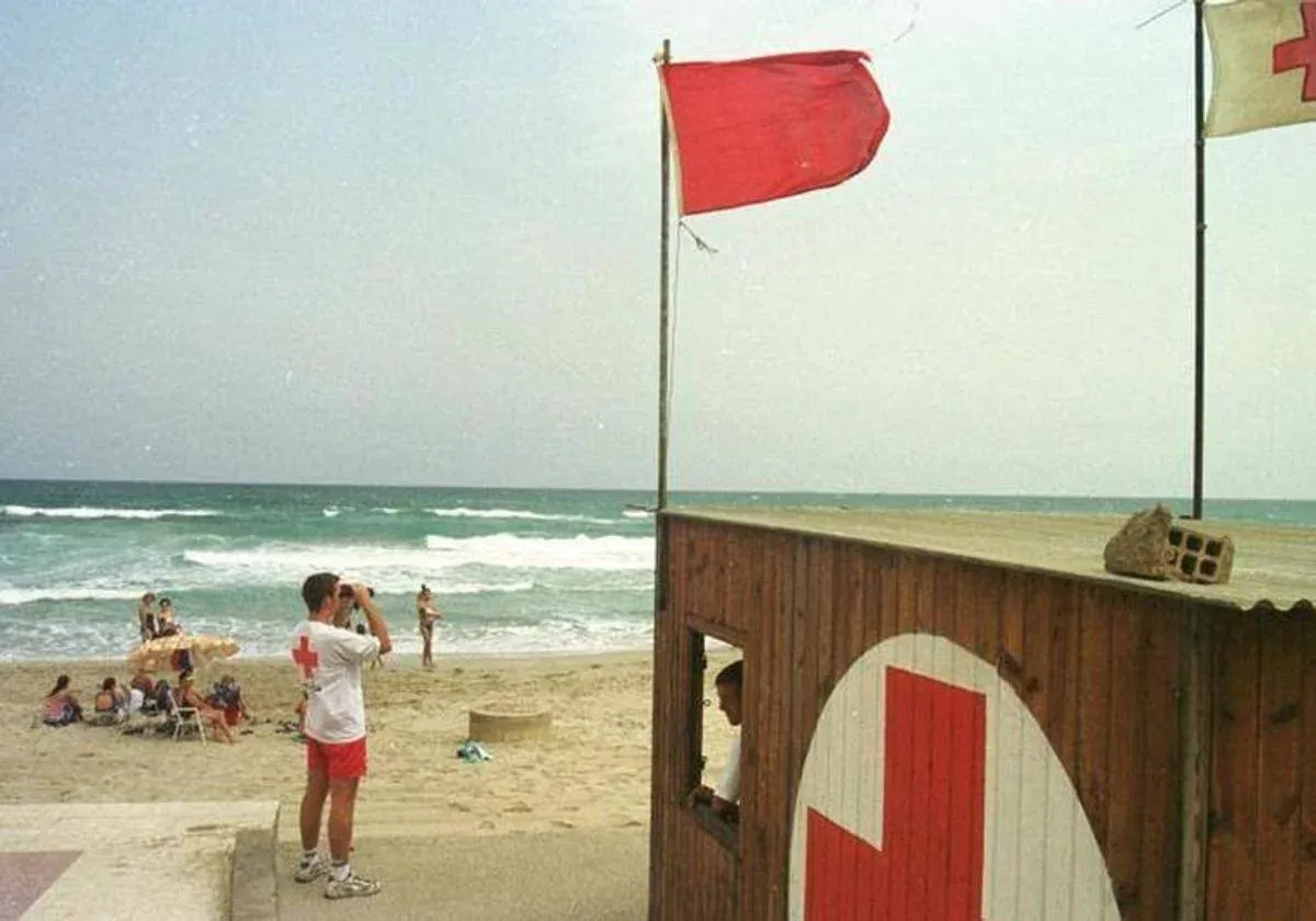 A red flag (Bandera ROJA) flying on a Costa Blanca beach, indicating that swimming is prohibited due to danger.