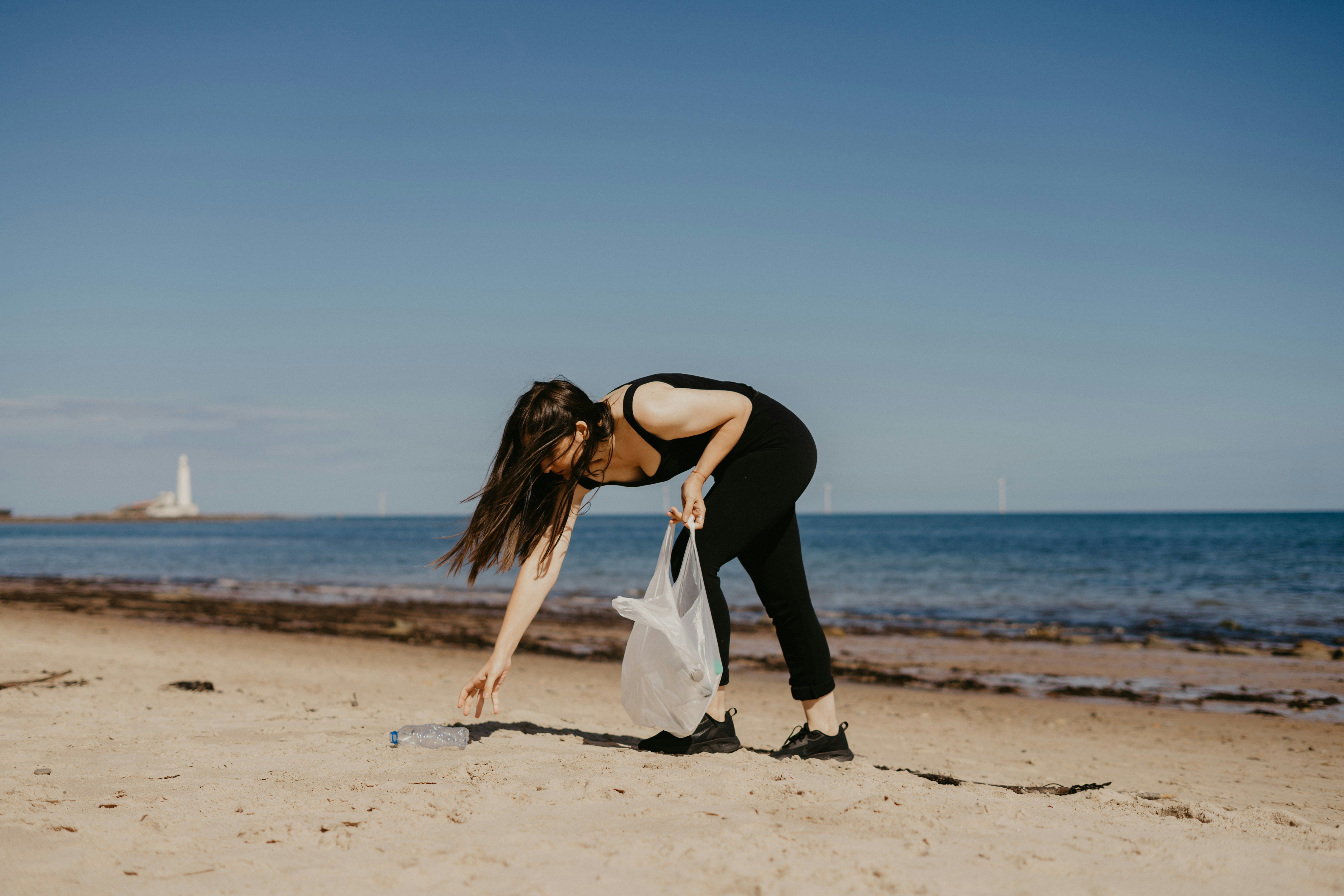 a woman cleaning the beach from plastic